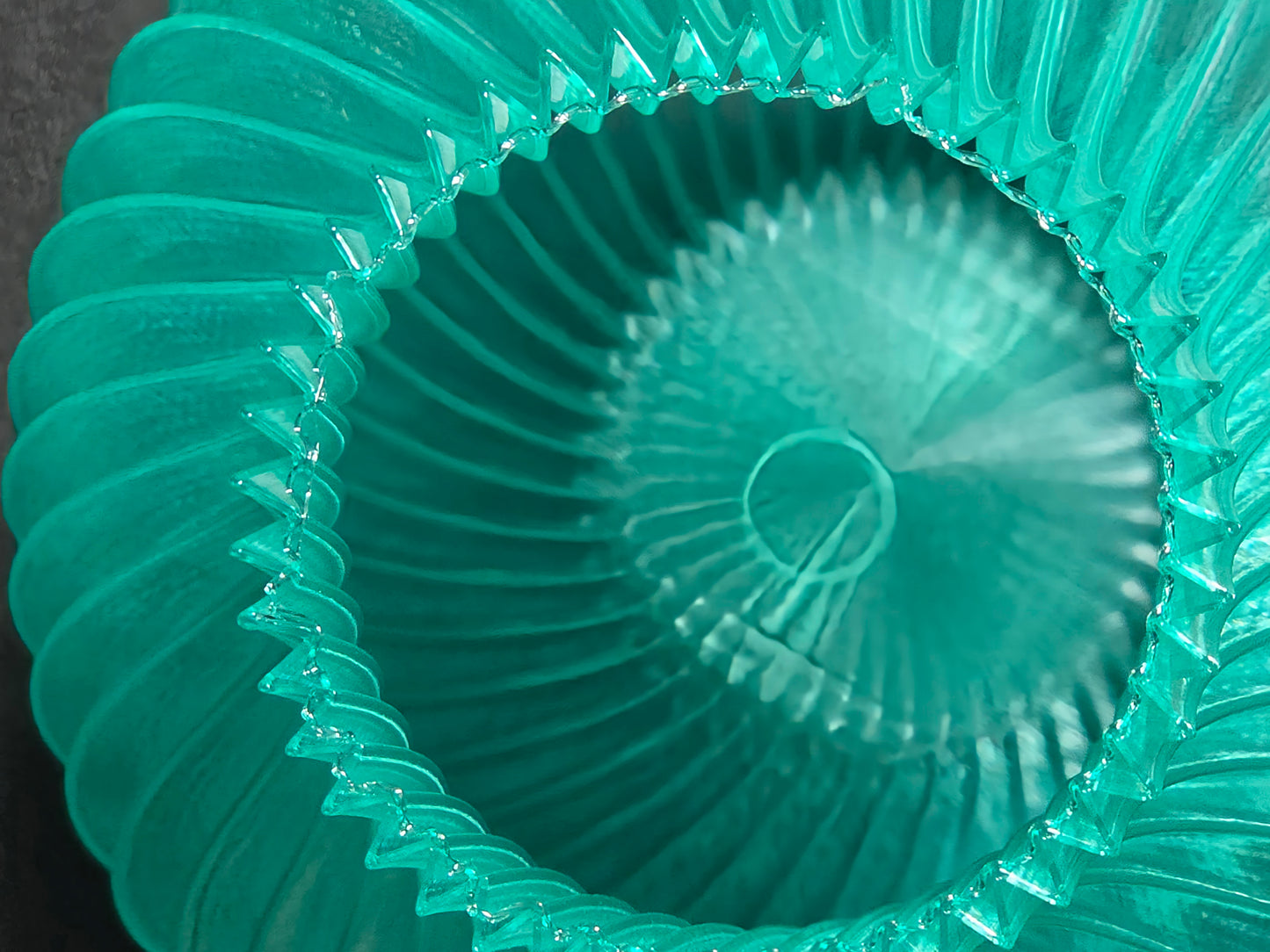 Close-up of a teal vase with textured design on a black background