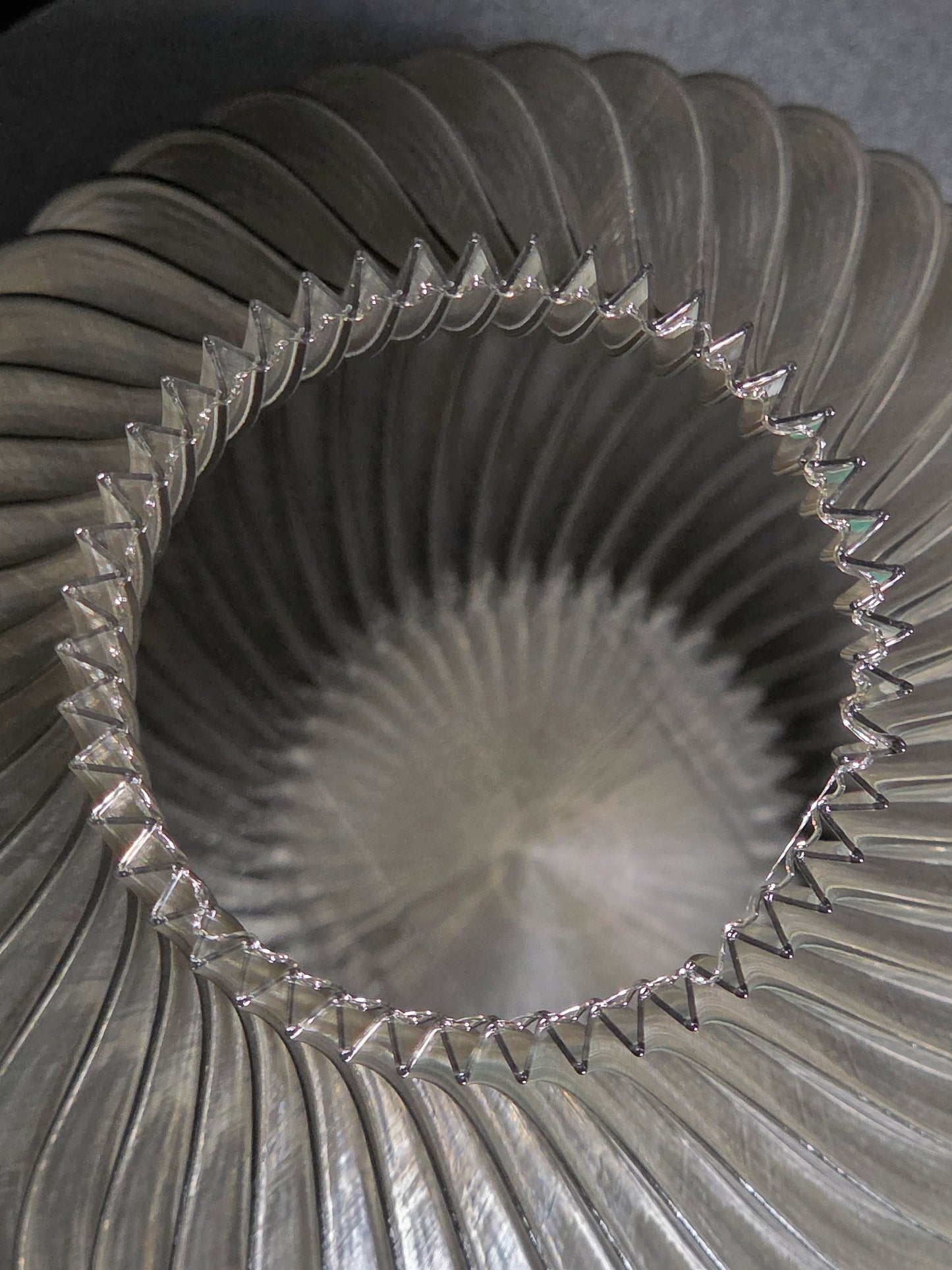 Close-up of the interior of  a translucent gray, ribbed vase  with a textured surface.