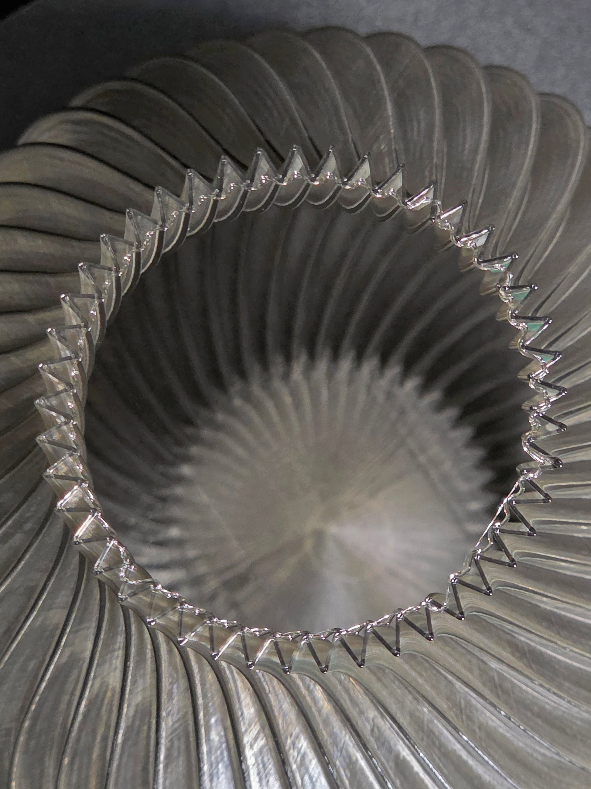 Close-up of the interior of  a translucent gray, ribbed vase  with a textured surface.