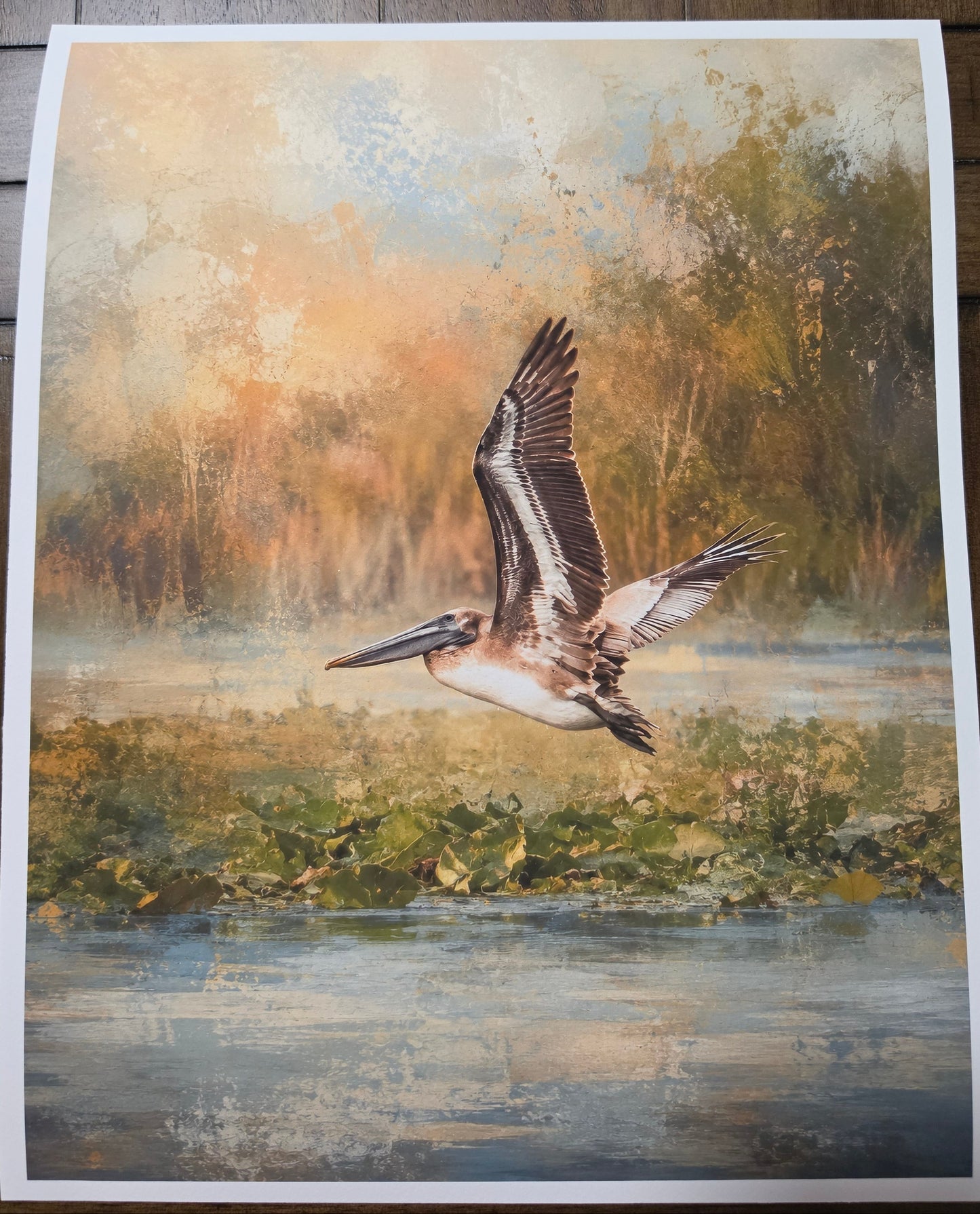 Art print of a pelican flying over water with a natural landscape background
