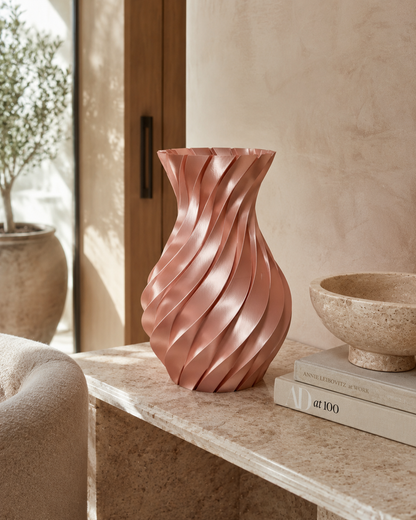 Decorative rose gold vase on a shelf with books and a plant in the background