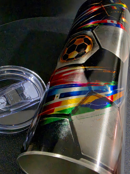 Metallic cup with soccer ball design and world flags on a reflective surface