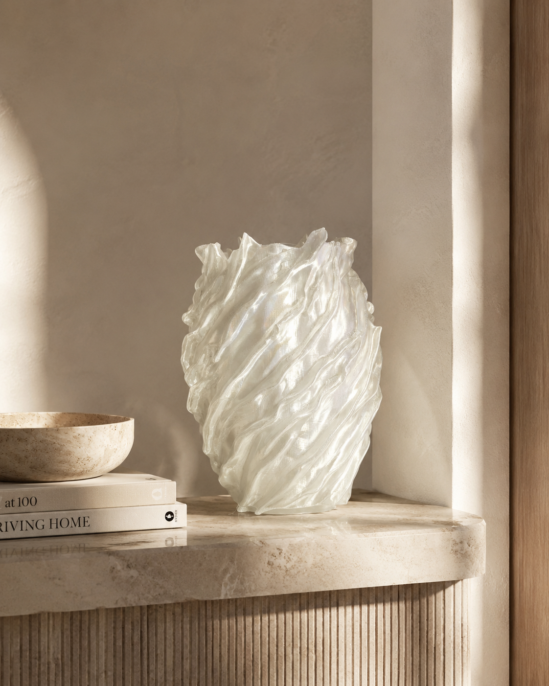 White textured vase on a shelf with books and a bowl in a softly lit room.